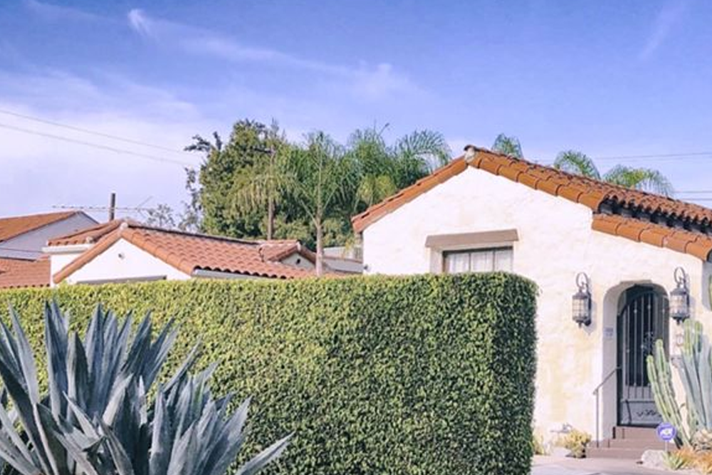 a house with a hedge and a blue sky