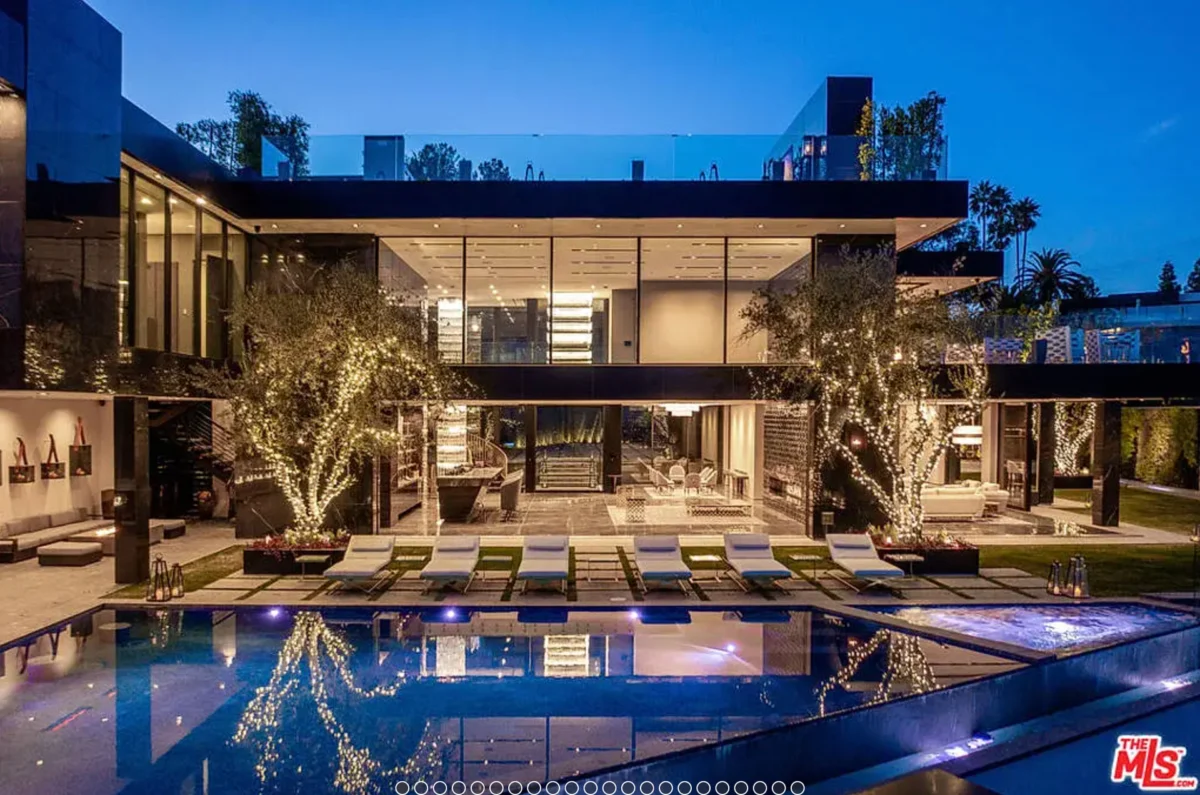 a pool with lights and chairs in front of a house