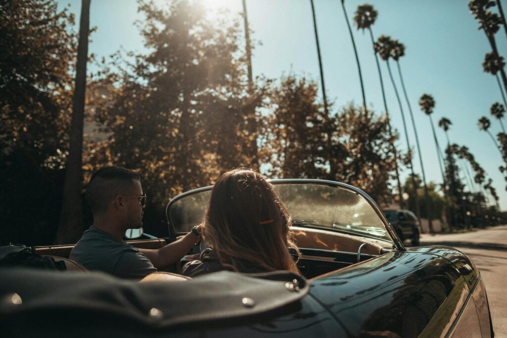 A man and woman driving a classic convertible in sunny Los Angeles.