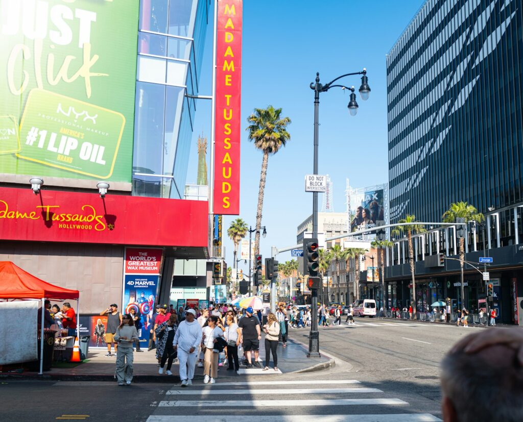 a group of people walking across a street next to tall buildings