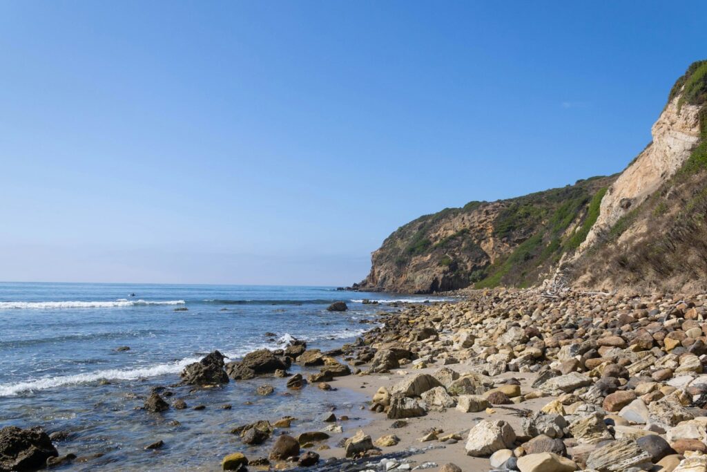 A rocky beach next to the ocean under a blue sky