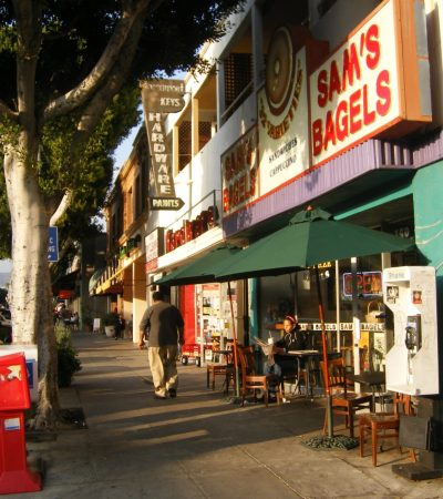 a man walking down a sidewalk with a sign on the side