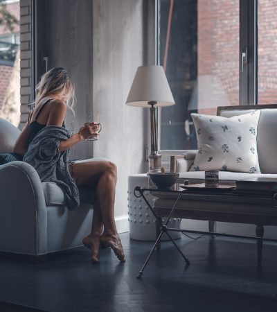 woman sitting on gray sofa chair holding mug