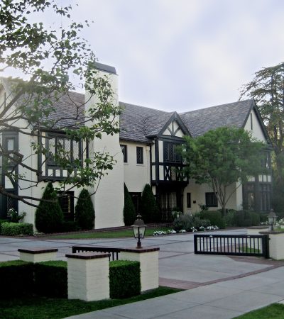 a large white house with a driveway and trees